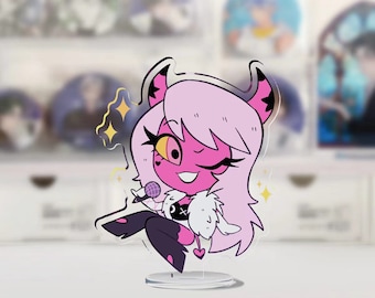 May include: A clear acrylic stand-up figure of a cartoon character with pink skin, white hair, and black horns. The character is holding a microphone and winking. The base is clear and the figure is 10cm tall.