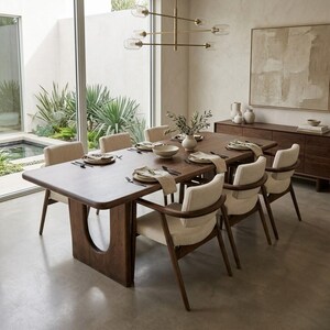 Puede incluir: Una gran mesa de comedor rectangular de madera oscura con una base en forma de U, rodeada de seis sillas con asientos tapizados en color beige claro y marcos de madera curvados. La mesa está puesta con platos blancos y cubiertos.