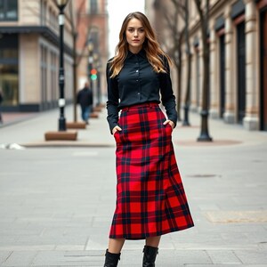 May include: A woman wearing a black button-down shirt and a red and black plaid skirt. She is standing on a city street.