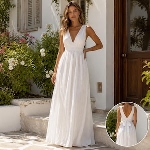 May include: A floor-length white sleeveless dress with a deep V-neckline and a fitted waist. The skirt features a flowing, pleated design. An inset shows the back of the dress, which has a deep V-back and a tied bow detail at the waistline.