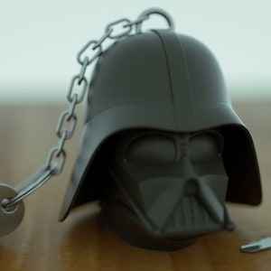 Puede incluir: Un llavero negro de Darth Vader con una cadena plateada y dos llaves plateadas.