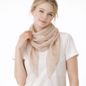 May include: A white ceramic mug with a black handle and the text "But First, Coffee" in a bold, black font. The mug is set against a blurred background, suggesting a cozy setting.