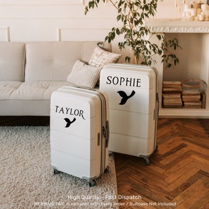 Peut inclure: Deux valises blanches avec des autocollants de queue de sir&egrave;ne noirs et des noms personnalis&eacute;s "Taylor" et "Sophie".