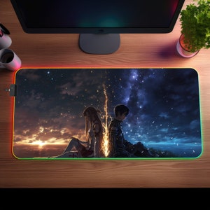 Könnte beinhalten: Eine schwarze und blaue Gaming-Mausmatte mit einem bunten Rand. Die Mausmatte zeigt eine Anime-Illustration von zwei Figuren, die Rücken an Rücken vor einem sternenklaren Nachthimmel sitzen.