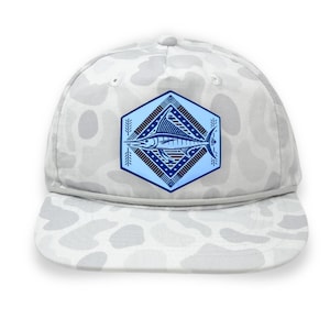May include: A white camouflage-patterned baseball cap with a blue and red fish emblem. The emblem is a stylized illustration of a fish within a hexagonal frame. The cap has a flat brim and a gray adjustable strap.