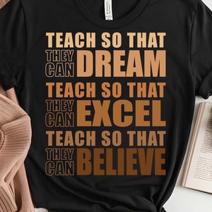 May include: Black t-shirt with the text "TEACH SO THAT THEY CAN DREAM TEACH SO THAT THEY CAN EXCEL TEACH SO THAT THEY CAN BELIEVE" in brown text.