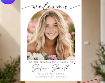 May include: White welcome sign with a black calligraphy font that says "welcome". The sign has a photo of a young woman with blonde hair in a floral archway. The text below the photo says "To the graduation party of Sofia Smith, Class of 2025, Lincoln High School".