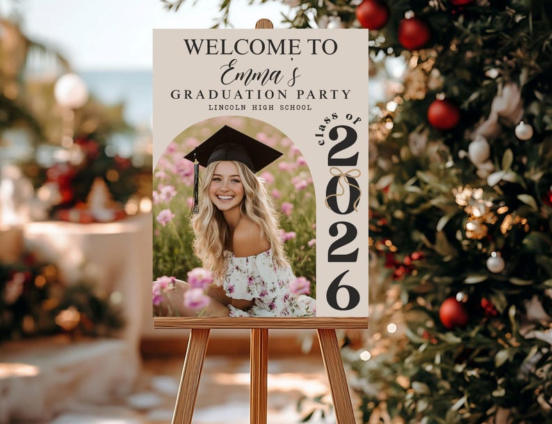 Pode incluir: Um cavalete de madeira com um letreiro de boas-vindas para uma festa de formatura. O letreiro diz "Bem-vindo &agrave; festa de formatura de Emma, Lincoln High School, Turma de 2026". Uma foto de uma graduada sorrindo &eacute; apresentada.
