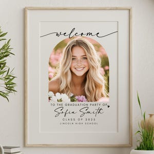 Peut inclure: Une pancarte de f&ecirc;te de fin d'&eacute;tudes blanche avec une arche noire et le texte "Bienvenue &agrave; la f&ecirc;te de fin d'&eacute;tudes de Sofia Smith, Classe de 2023, Lincoln High School". Une photo d'une jeune femme aux longs cheveux blonds est dans l'arche.