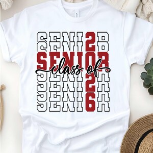May include: White t-shirt with the words "SENIOR class of 2026" in a stacked design. The word "SENIOR" is in a bold red font, while the rest of the text is in black. The shirt is a classic crew neck.