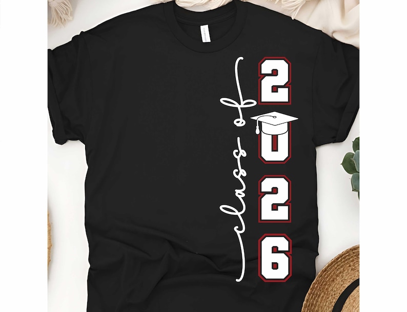 May include: Black t-shirt with the words "Class of 2026" in white script and red-outlined numbers. A graduation cap graphic is above the "2026" text. The shirt is a classic crew neck style.