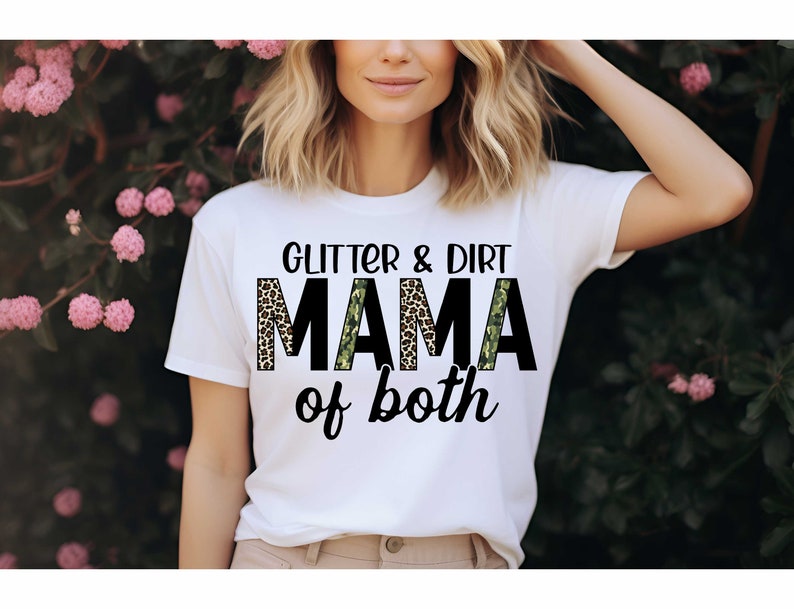 Pode incluir: Camiseta branca com o texto "Glitter & Dirt Mama of both" em preto com uma estampa de leopardo e um padr&atilde;o de camuflagem atr&aacute;s do texto.