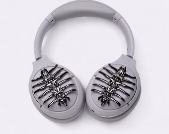 May include: Gray over-ear headphones with a unique design featuring black, skeletal-like accents on each earcup.