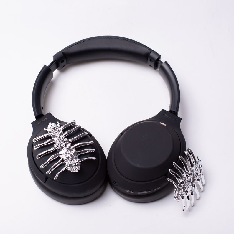 May include: Black wireless headphones with silver skeleton-shaped embellishments on each earcup.