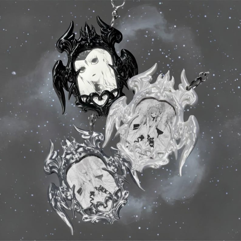 May include: Three gothic-style pendants with portraits. The pendants have ornate frames in black, silver, and white. Each frame features a portrait of a person. The pendants are suspended from a chain against a starry background.