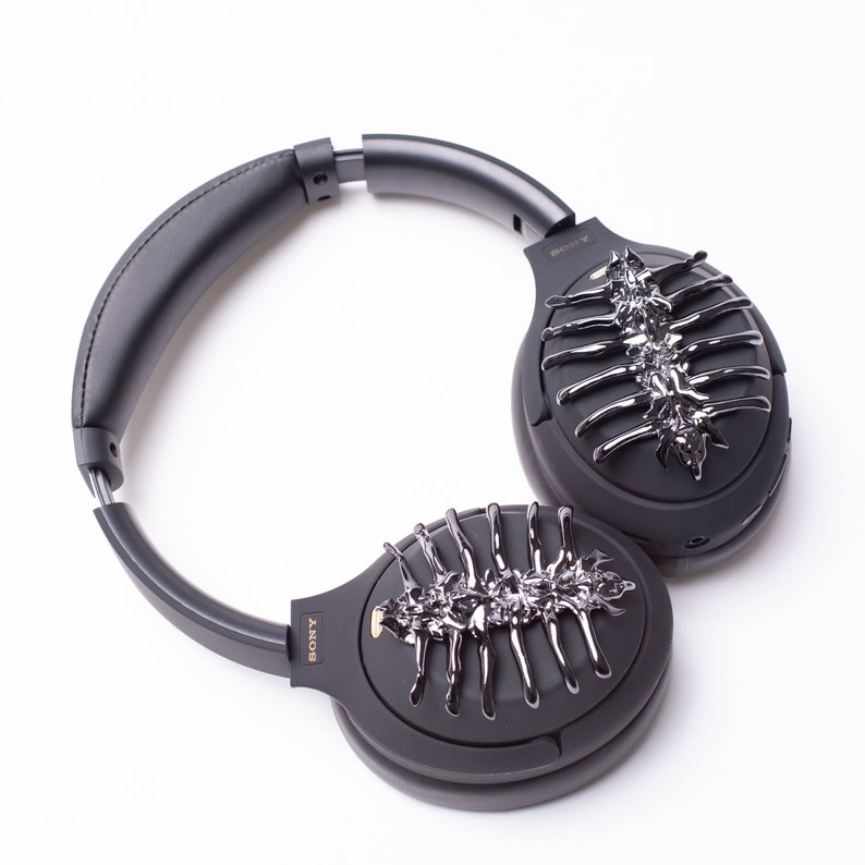 May include: Black over-ear headphones with a silver, skeletal design on each earcup. The headphones have a black headband and the word "SONY" is printed on the earcups.