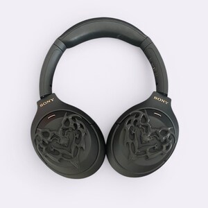 May include: Black over-ear headphones with a gold "SONY" logo on each earcup. The earcups feature a black and gold intricate design.