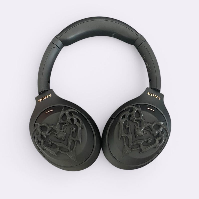 May include: Black over-ear headphones with a gold "SONY" logo on each earcup. The earcups feature a black and gold intricate design.