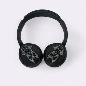 Puede incluir: Auriculares inal&aacute;mbricos negros con un dise&ntilde;o plateado intrincado en cada auricular.