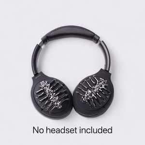 May include: Black headphones with a silver and black decorative design on each earcup. The text "SONY" is visible on the left earcup. "No headset included" is written below the headphones.