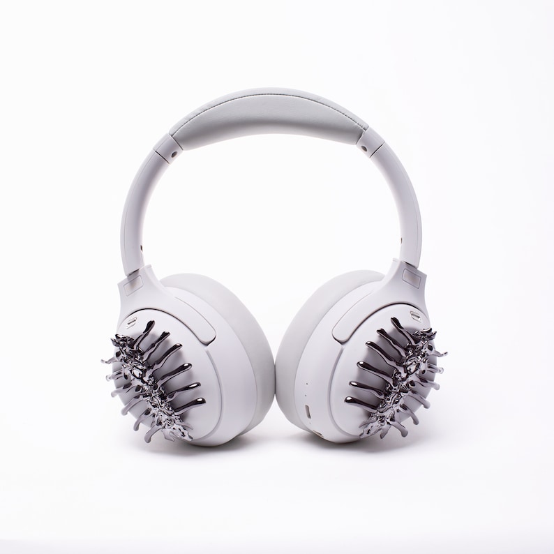 May include: White wireless headphones with a silver, spiky design on each earcup.