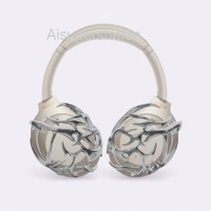 May include: A pair of gold wireless headphones with a silver, intricate, geometric design on the earcups. The headphones have a headband that is adjustable and padded for comfort. The brand name "SONY" is visible on the earcups.