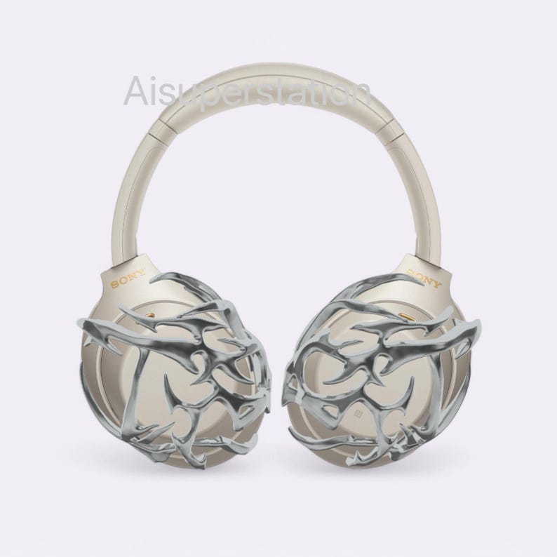 May include: A pair of gold wireless headphones with a silver, intricate, geometric design on the earcups. The headphones have a headband that is adjustable and padded for comfort. The brand name "SONY" is visible on the earcups.