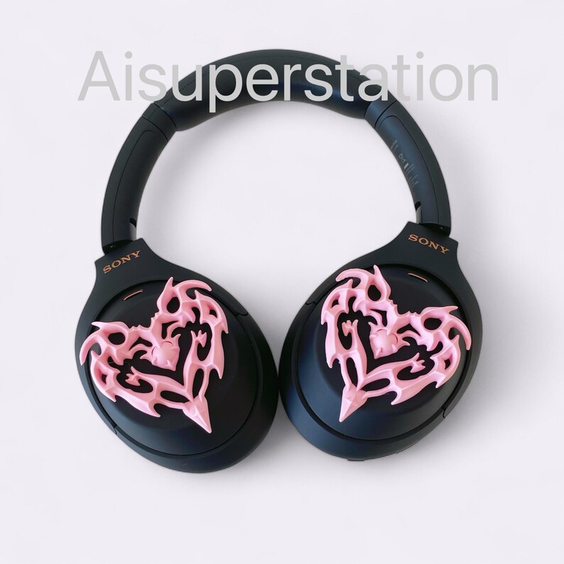 May include: Black over-ear headphones with pink heart-shaped designs on each earcup. The headphones have the word "SONY" written on each earcup.