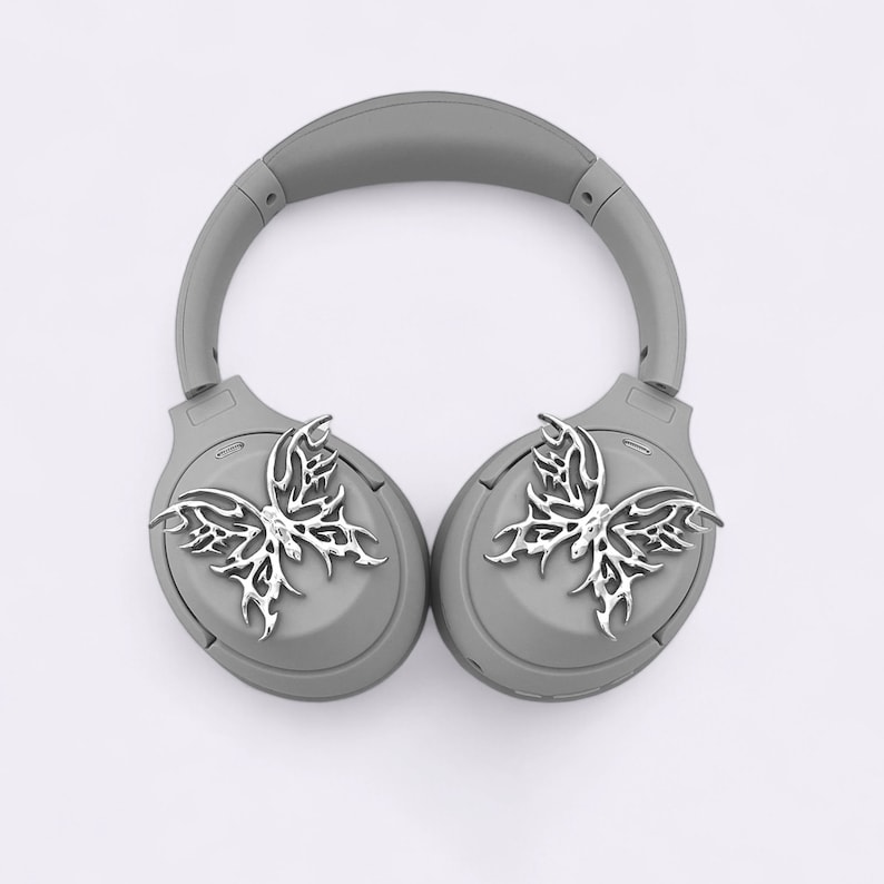 May include: Gray wireless headphones with silver butterfly-shaped embellishments on each earcup.