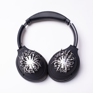 May include: Black over-ear headphones with a silver, spiky design on each earcup. The headphones have the word "SONY" printed on each earcup.