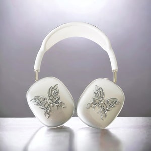 May include: White over-ear headphones with a silver butterfly design on each earcup.