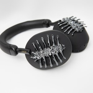May include: Black over-ear headphones with a silver, decorative design on the earcups. The headphones have the word "SONY" printed on the side.