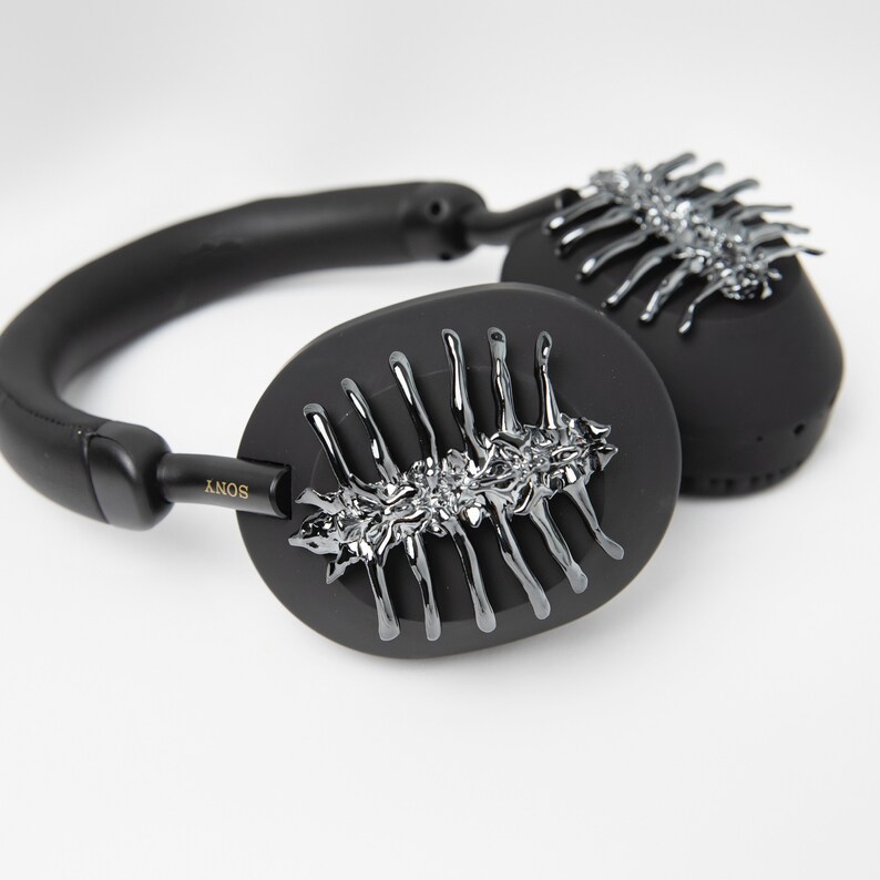 May include: Black over-ear headphones with a silver, decorative design on the earcups. The headphones have the word "SONY" printed on the side.