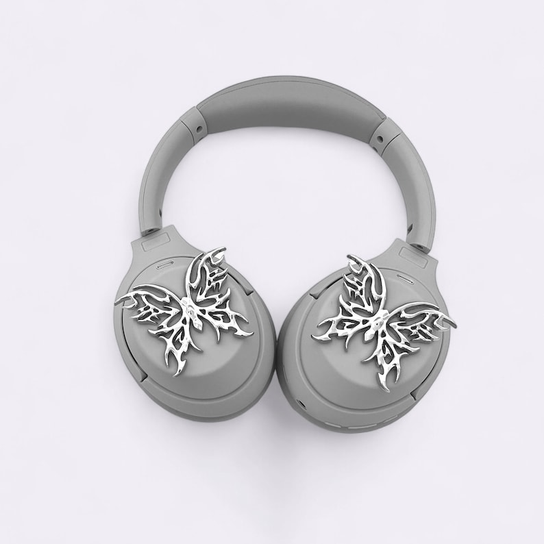 May include: Gray wireless headphones with silver butterfly-shaped embellishments on each earcup.