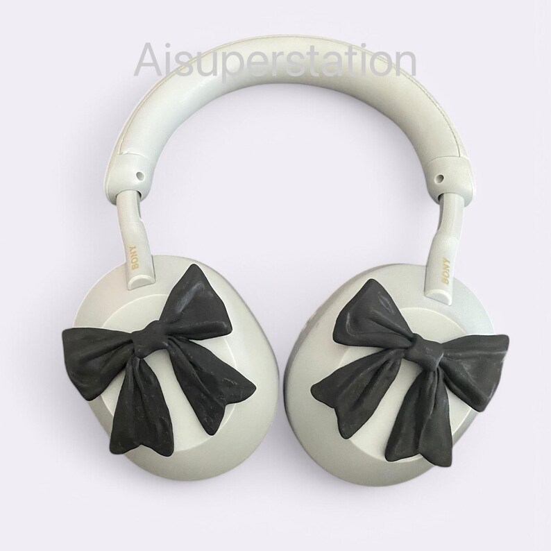 K&ouml;nnte beinhalten: Wei&szlig;e Over-Ear-Kopfh&ouml;rer mit schwarzen Schleifen an jedem Ohrpolster. Die Kopfh&ouml;rer haben den Schriftzug "SONY" auf der Seite jedes Ohrpolsters.