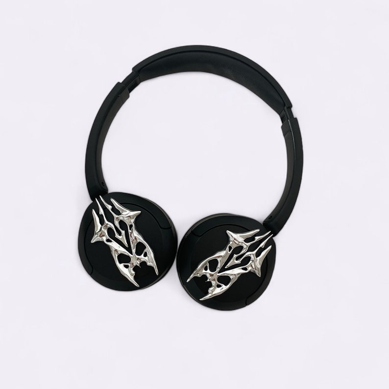 Puede incluir: Auriculares negros con un dise&ntilde;o de calavera plateada en cada auricular.