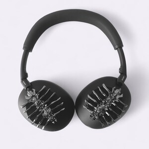 May include: Black over-ear headphones with a silver, skeletal-like design on each ear cup. The headphones have a padded headband and the brand name "SONY" is visible on the arms.