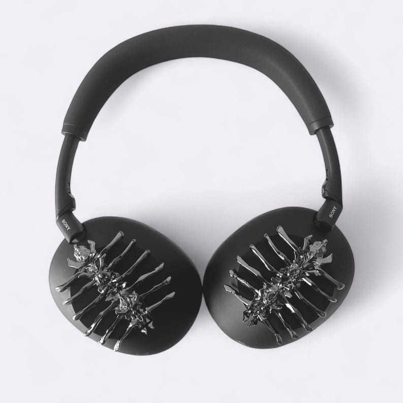 May include: Black over-ear headphones with a silver, skeletal-like design on each ear cup. The headphones have a padded headband and the brand name "SONY" is visible on the arms.