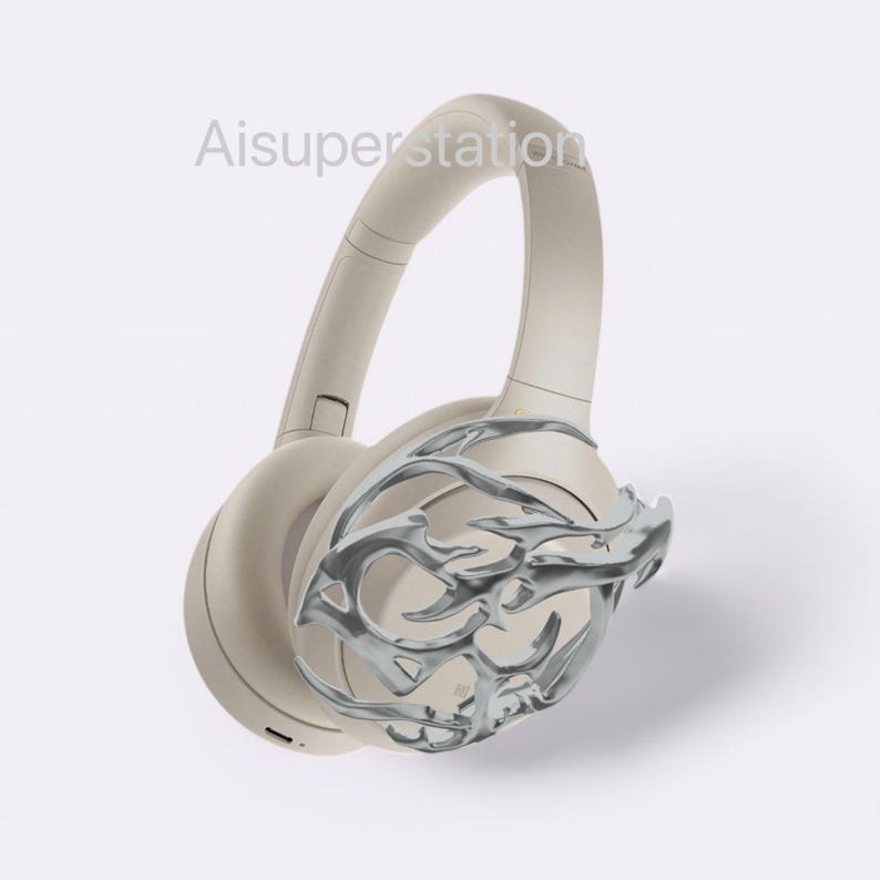 May include: Beige wireless headphones with a silver decorative design on one earcup.