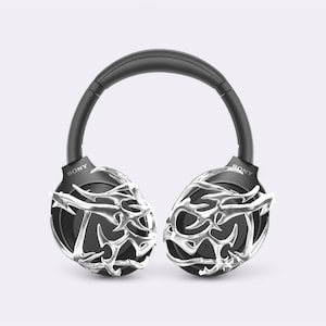 May include: Black over-ear headphones with a silver, intricate, geometric design on the earcups. The headphones have the word "SONY" printed on each earcup.