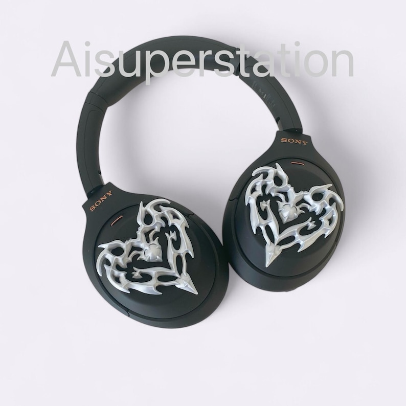May include: Black wireless headphones with a silver heart design on each earcup. The headphones have the word "SONY" printed on each earcup.