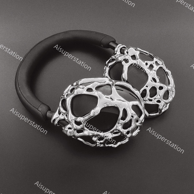 May include: A pair of black headphones with silver, textured earcups. The earcups have a unique, organic, and abstract design.