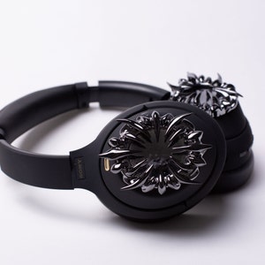 May include: Black over-ear headphones with a decorative, black metal design on the earcups. The headphones have the word "SONY" printed on the side.