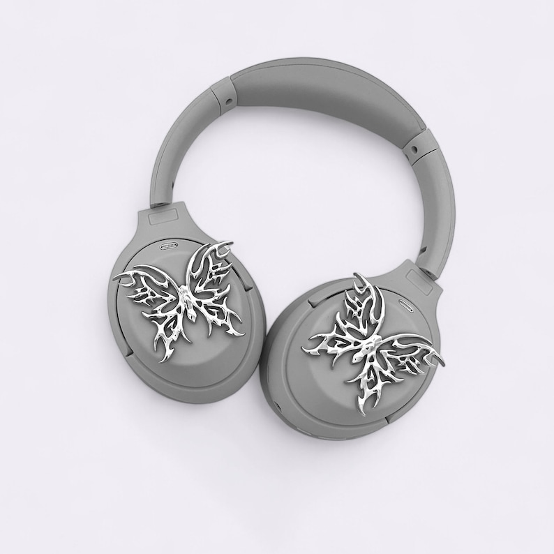 May include: Gray wireless headphones with a silver butterfly design on each earcup.