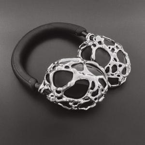 May include: Silver headphones with a unique, textured, organic-looking design. The headphones have a black headband.