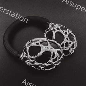May include: Silver headphones with a unique, textured, and abstract design. The headphones have a black headband.