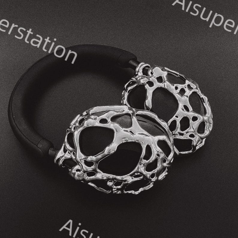 May include: Silver headphones with a unique, textured, and abstract design. The headphones have a black headband.