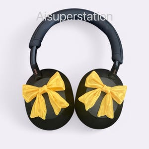 K&ouml;nnte beinhalten: Schwarze Over-Ear-Kopfh&ouml;rer mit gelben Schleifenakzenten an jedem Ohrpolster. Die Kopfh&ouml;rer tragen den Schriftzug "SONY" an der Seite.