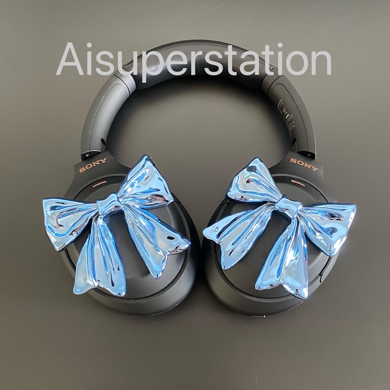 Pu&ograve; includere: Cuffie over-ear nere con fiocchi blu attaccati a ciascun padiglione. Le cuffie hanno la scritta "SONY" stampata su ciascun padiglione.