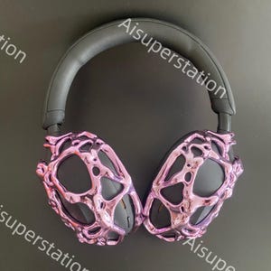 May include: Purple headphones with a unique, textured, metallic design. The headphones have a black headband and earcups.